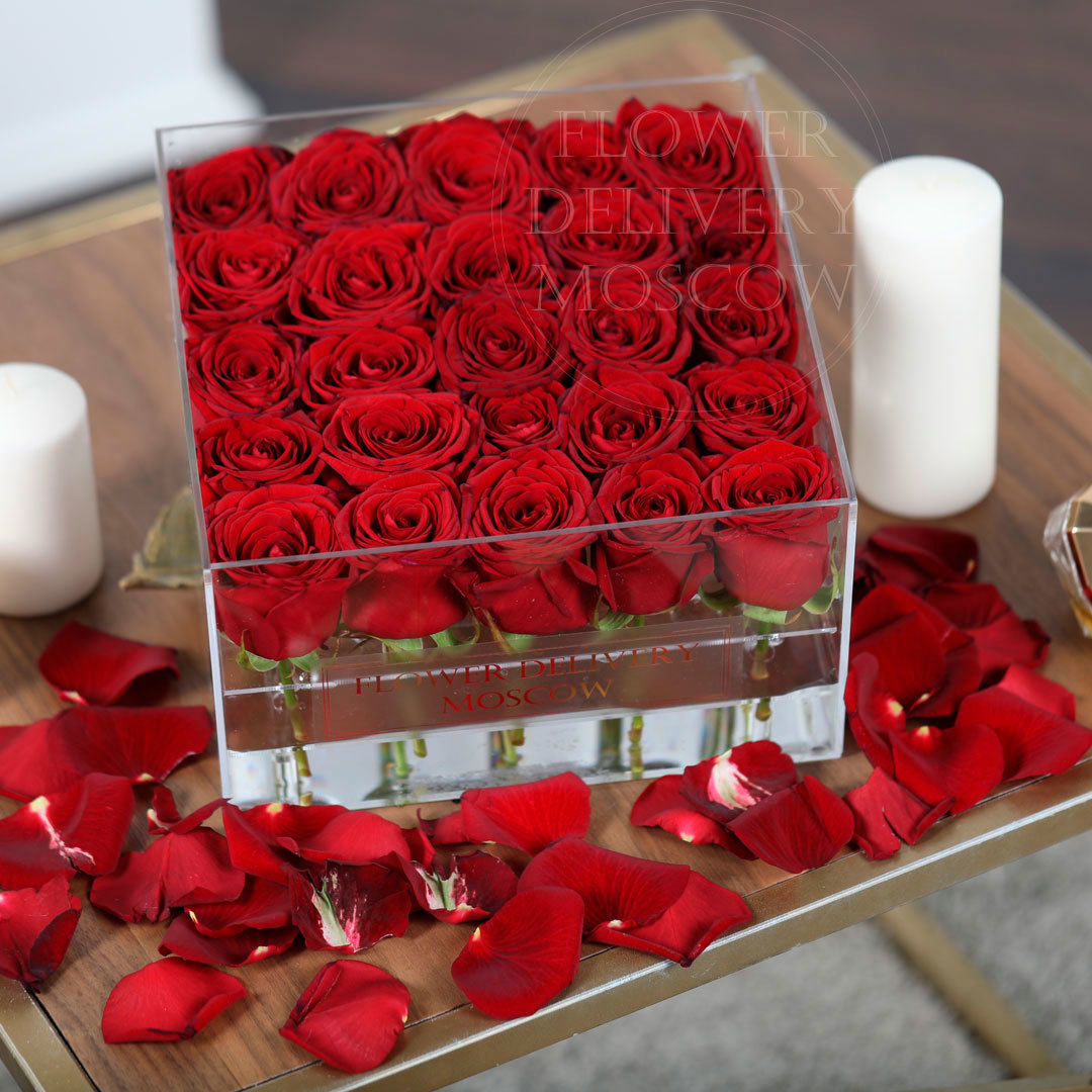 25 красных роз в стеклянной коробке на столе