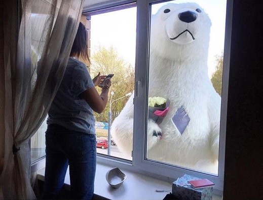 Белый медведь вручает букет цветов девушке на 5-м этаже